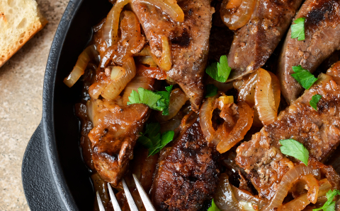 Fried liver with onions and apples on a concrete background