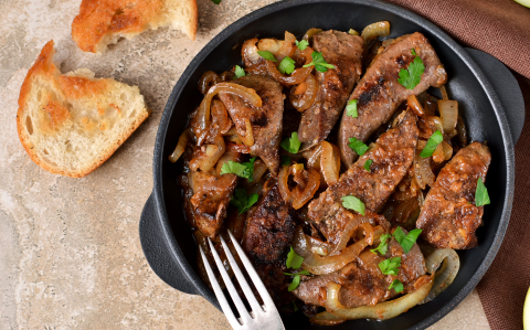 Fried liver with onions and apples on a concrete background